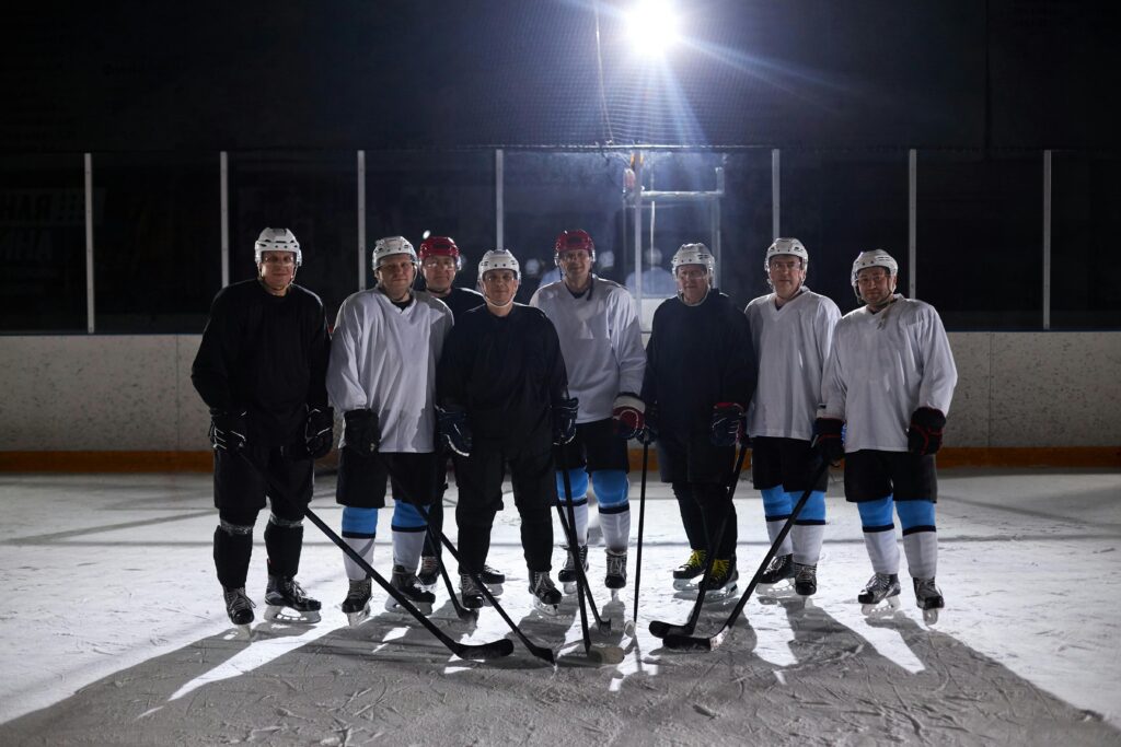 A team of male ice hockey players posing on the rink under bright lights.
